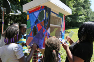 Youth at Lafayette Village Apartments paint a little free library