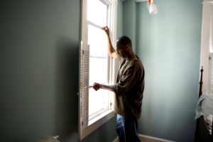 African American man opening window at his home