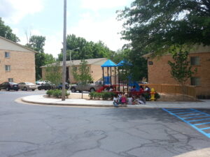 Exterior of three brick buildings at Maplewood Apartments and playground equipment